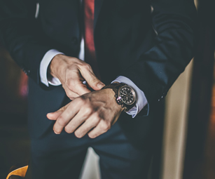 A man in a suit putting on his new watch. At CSW Insurance Brokers we can cover watches and other expensive belongings with a high net worth insurance policy.